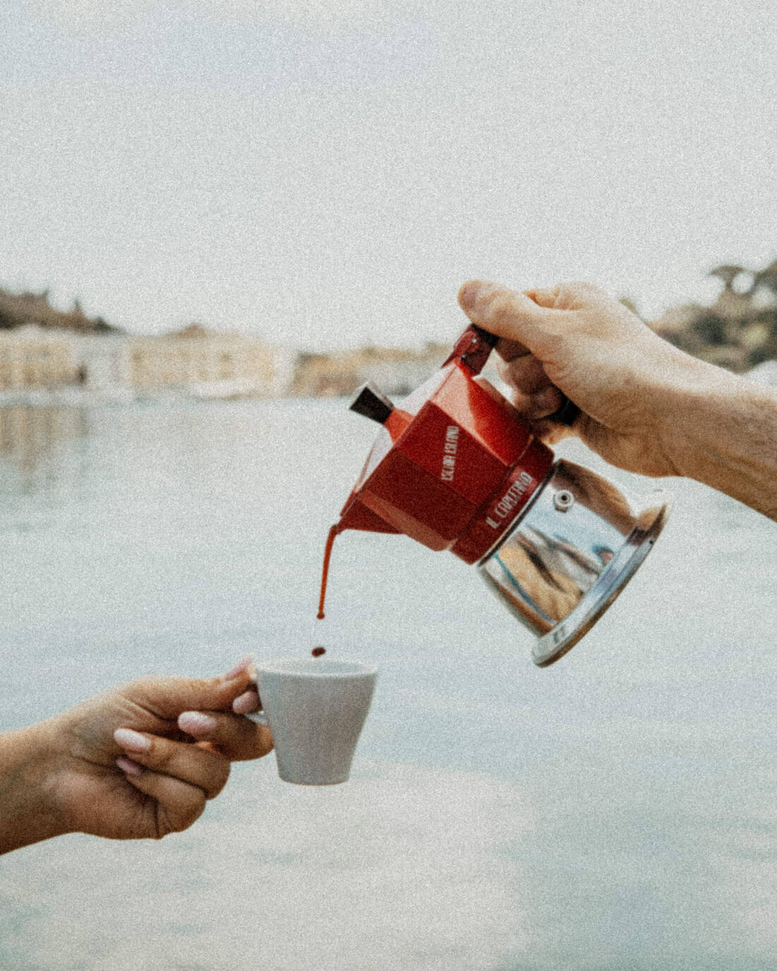 Caffè versato dalla moka con il porto d'Ischia sullo sfondo
